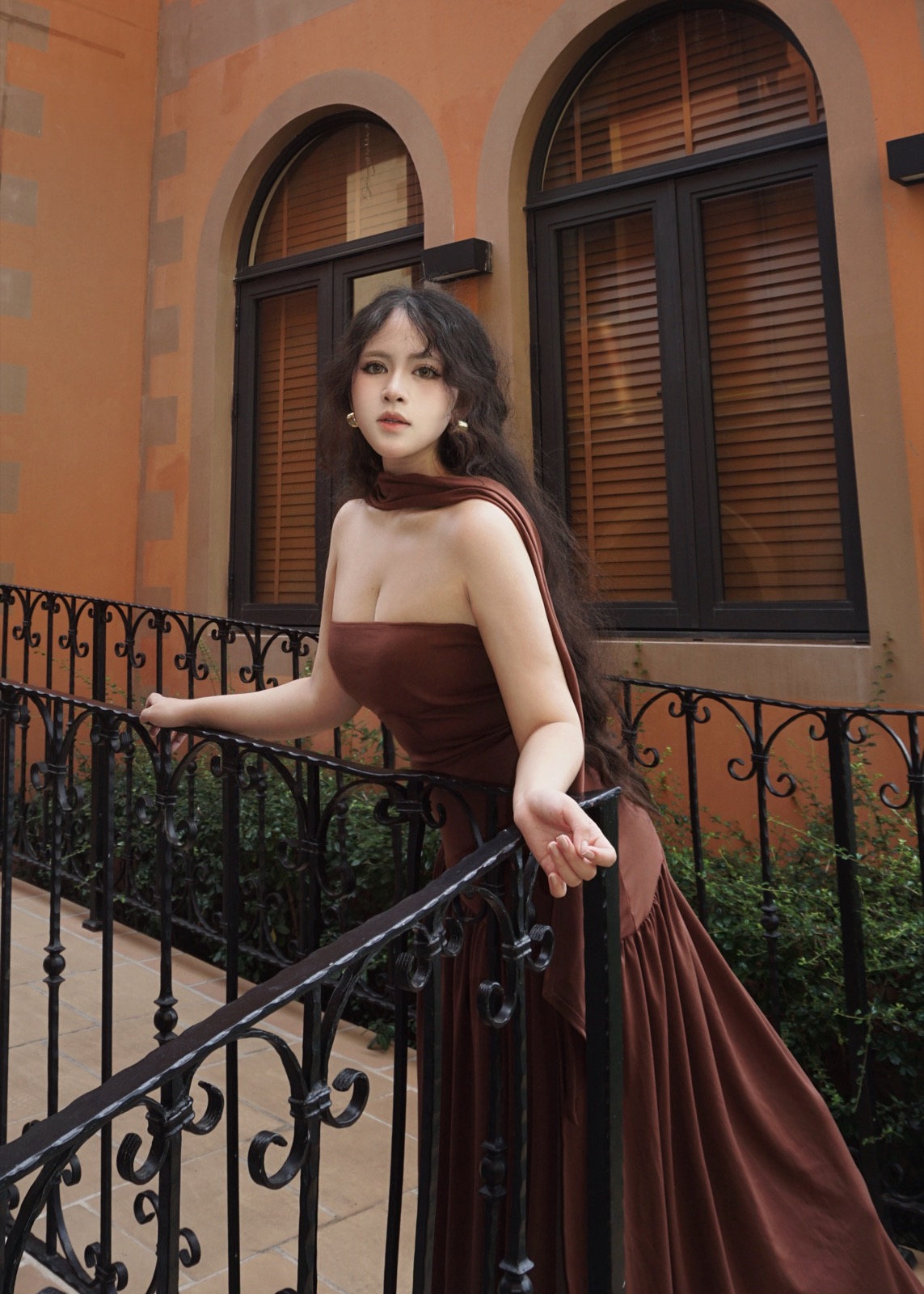 Clara in a brown dress on a sunlit balcony