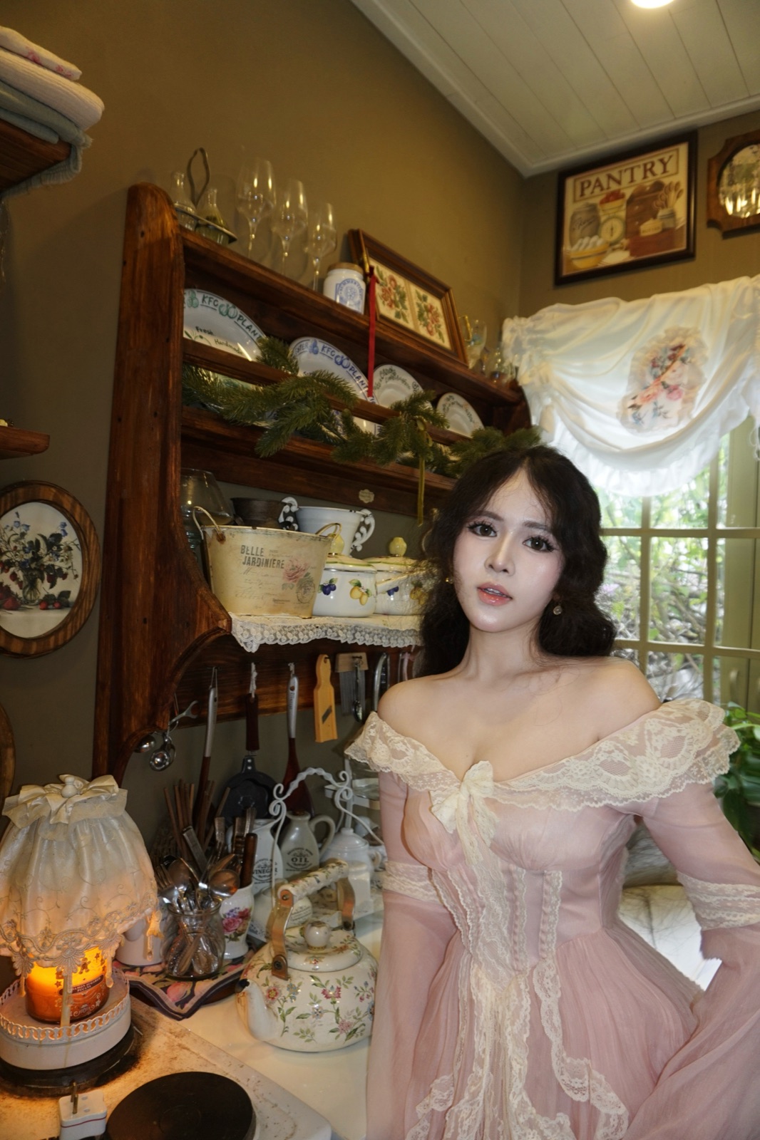 Clara in a pale pink dress inside a vintage cottage kitchen