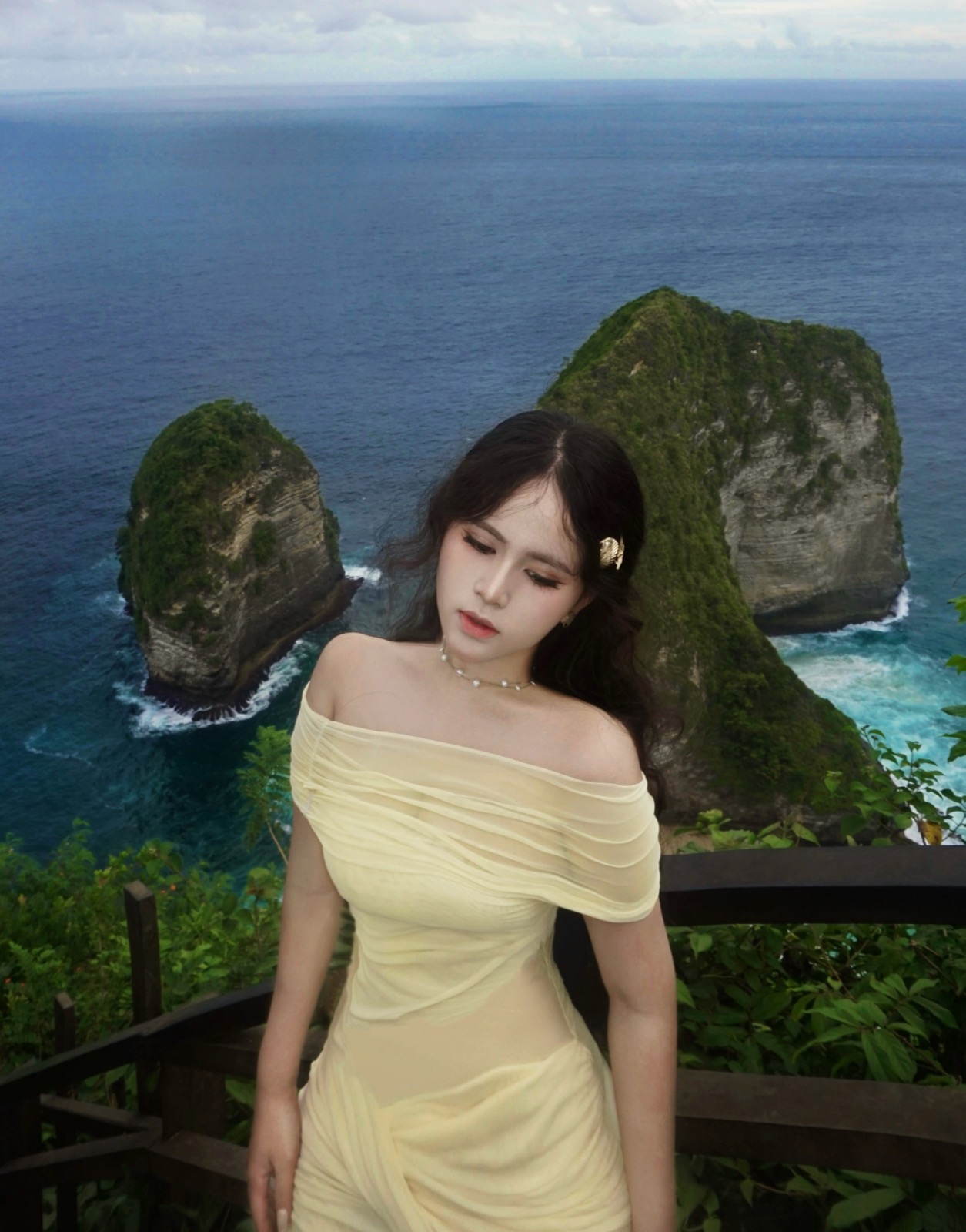 Clara in a pale yellow dress overlooking island cliffs