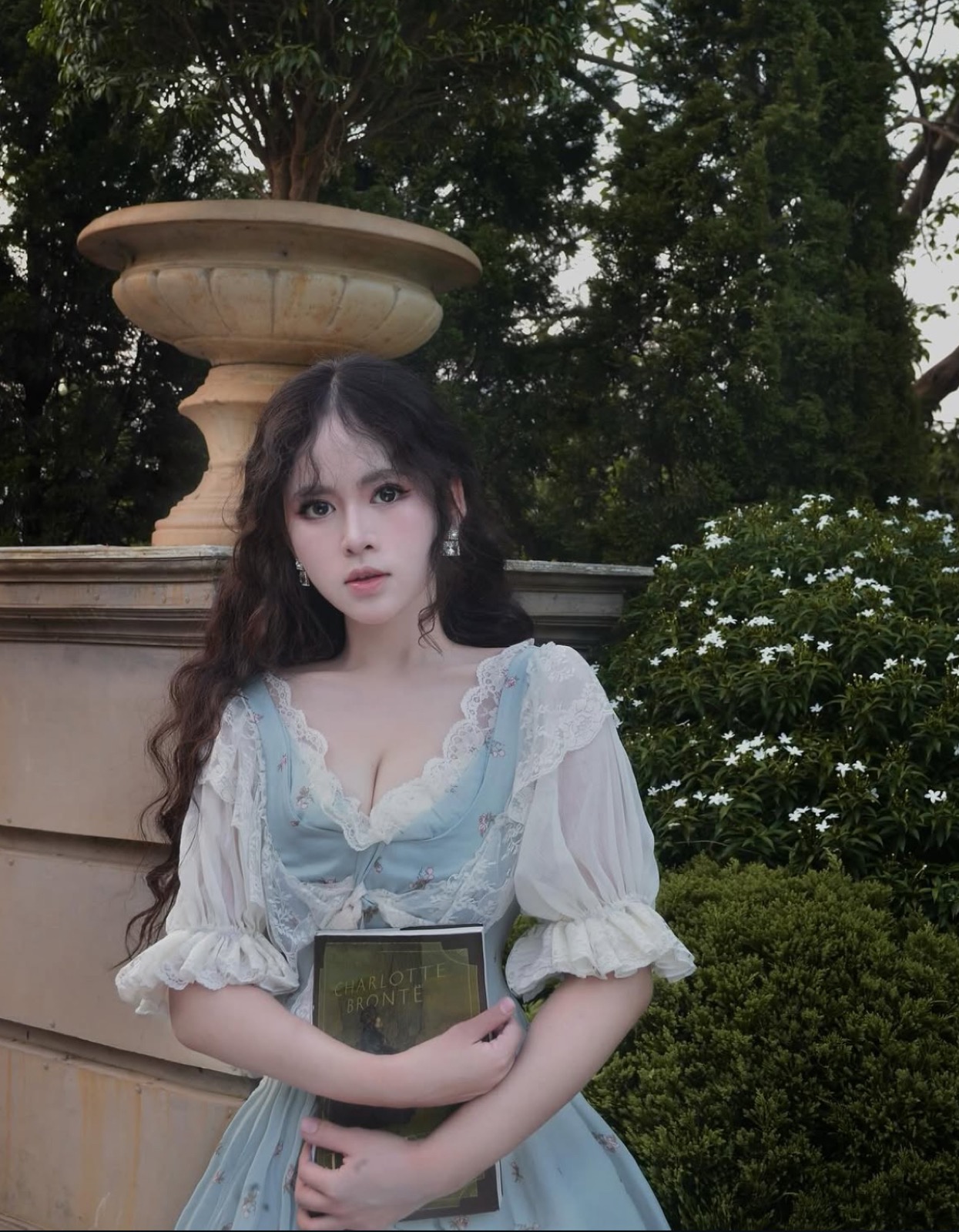 Clara holding a Charlotte Brontë book in a garden