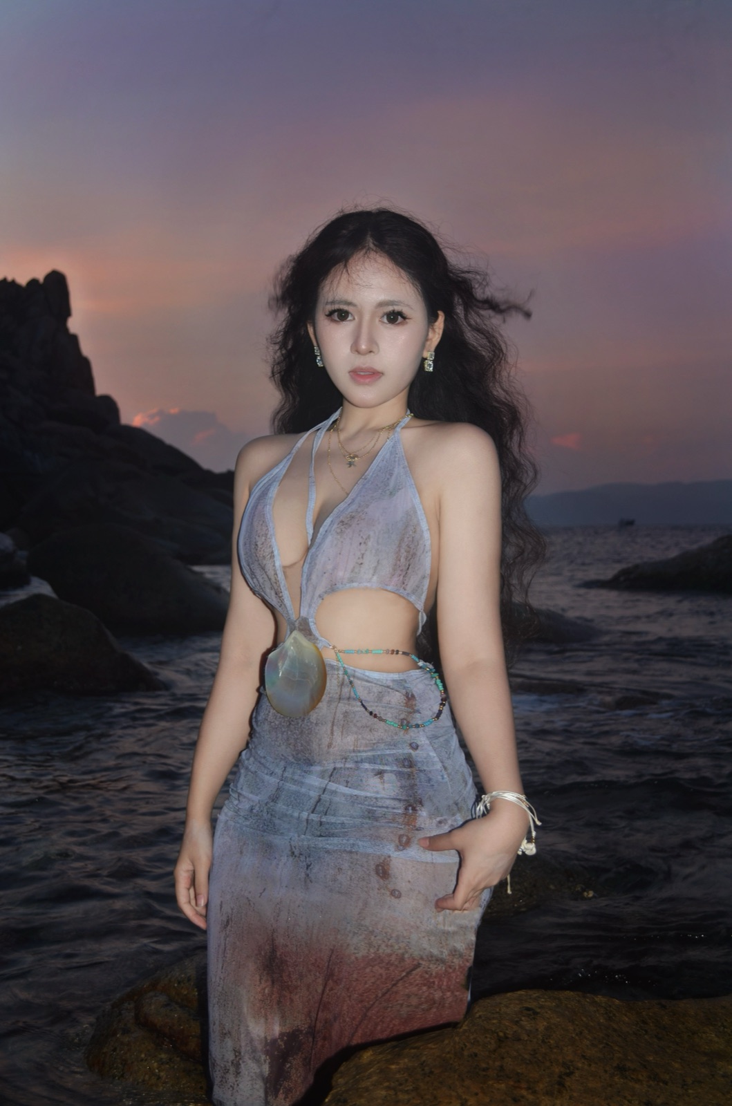 Clara standing on a rocky coast at dusk