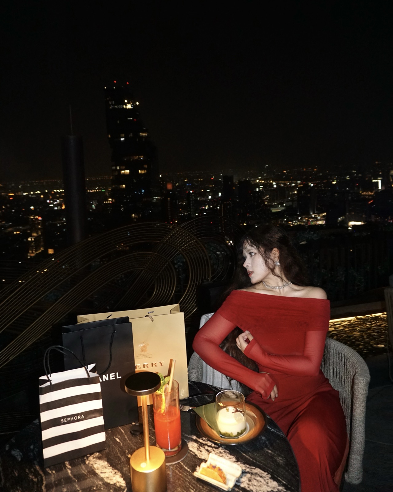Clara in a red dress overlooking the city at night