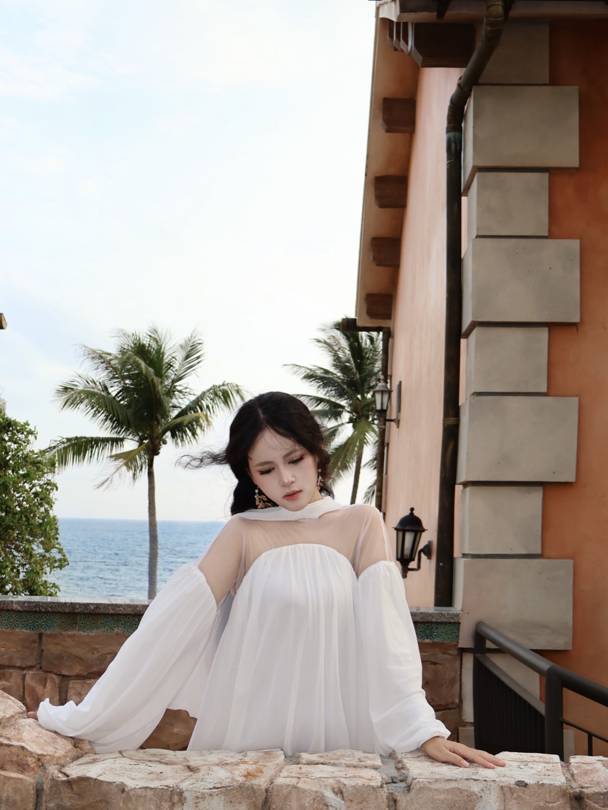Clara in white on a terrace overlooking the sea
