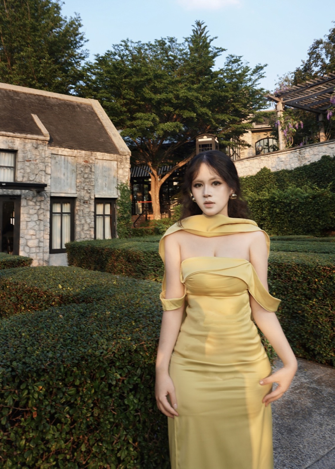Clara in a gold dress at a garden resort
